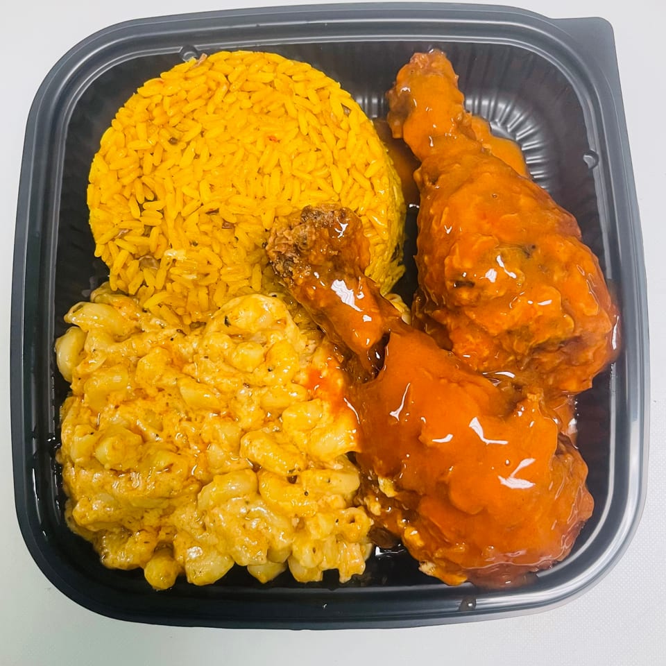 K&S Caribbean Cuisine meal with yellow rice, macaroni and cheese, and two glazed chicken drumsticks.