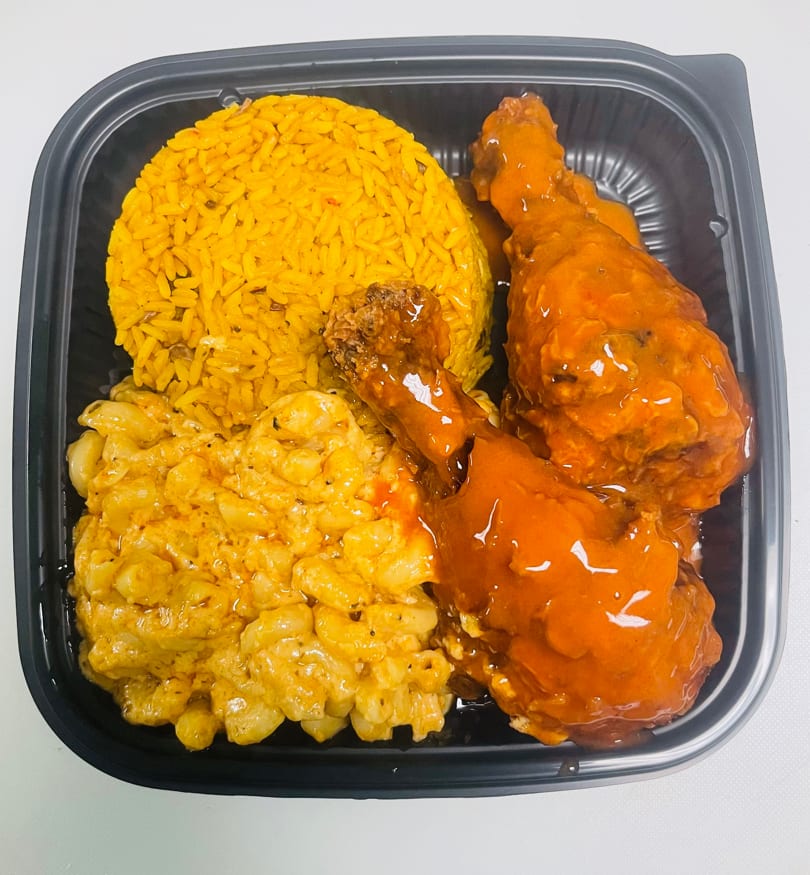 K&S Caribbean Cuisine meal with yellow rice, macaroni and cheese, and two glazed chicken drumsticks.