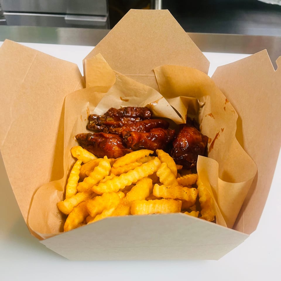 K&S Caribbean Cuisine's jerk chicken wings and crinkle-cut fries in a brown takeout box.